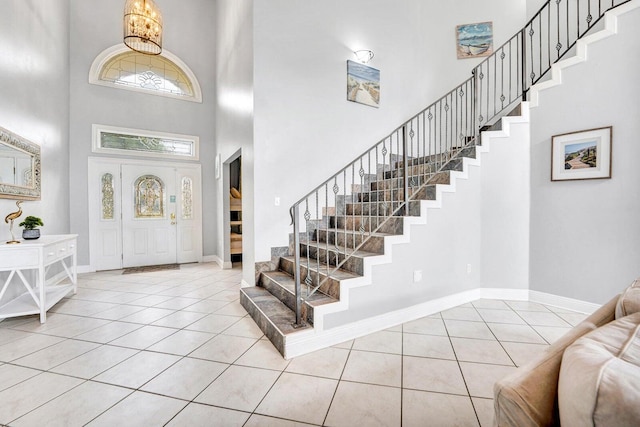 tiled foyer featuring an inviting chandelier and a high ceiling