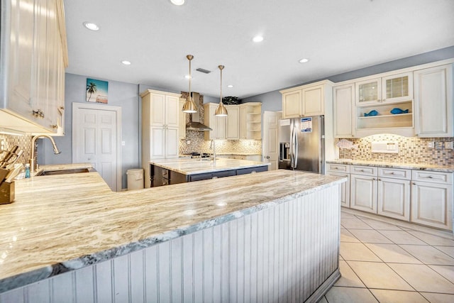 kitchen featuring stainless steel fridge with ice dispenser, tasteful backsplash, sink, and light stone counters