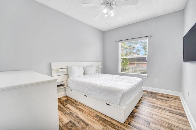 bedroom with ceiling fan, light wood-type flooring, and a textured ceiling