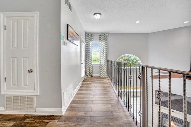 hallway with a textured ceiling and dark wood-type flooring