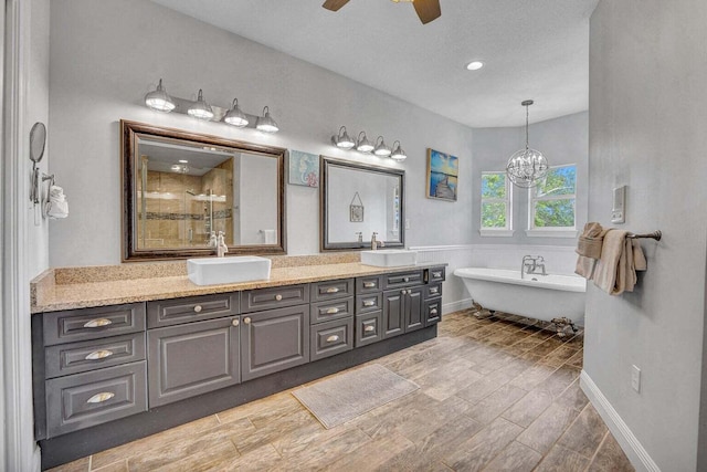 bathroom with ceiling fan with notable chandelier, double sink vanity, and a tub