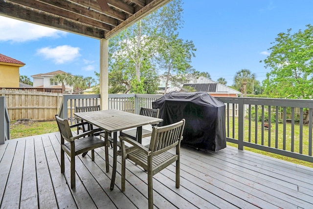 wooden terrace featuring a grill and a lawn