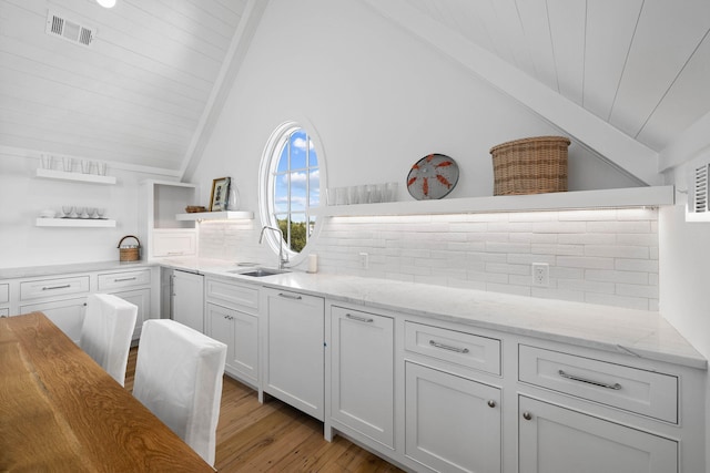 kitchen featuring white cabinetry, backsplash, light hardwood / wood-style flooring, light stone counters, and sink