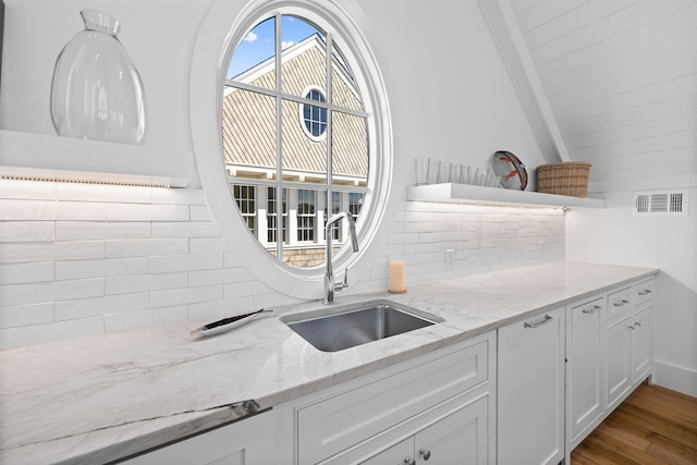 kitchen featuring white cabinets, sink, tasteful backsplash, light hardwood / wood-style flooring, and light stone countertops