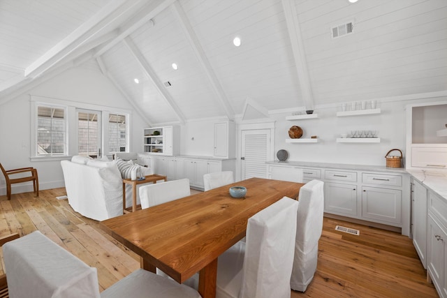 dining area featuring vaulted ceiling with beams and light wood-type flooring