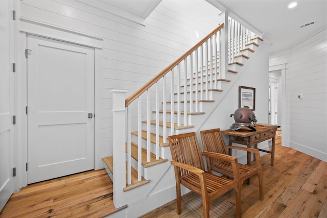 stairway with light hardwood / wood-style flooring and ornamental molding