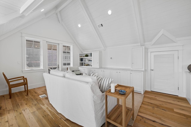 living room with lofted ceiling with beams, light hardwood / wood-style flooring, and built in shelves