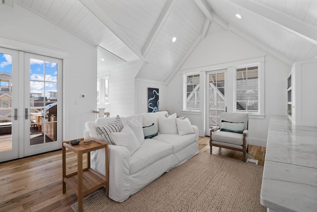 living room with french doors, light hardwood / wood-style floors, and vaulted ceiling with beams