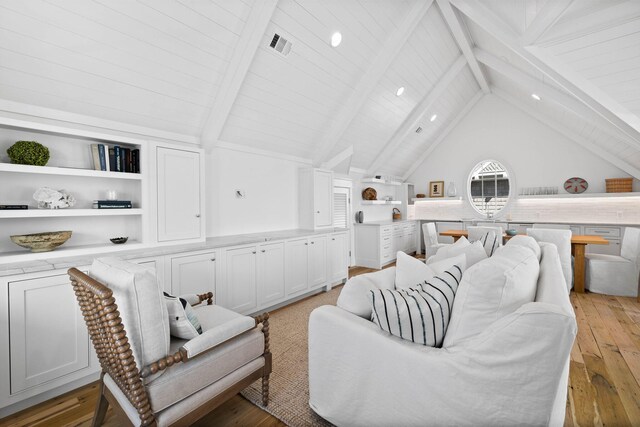 living room with lofted ceiling with beams, built in features, and light hardwood / wood-style floors