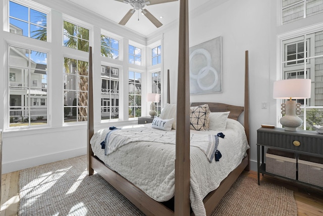 bedroom featuring hardwood / wood-style floors, ceiling fan, a towering ceiling, and multiple windows