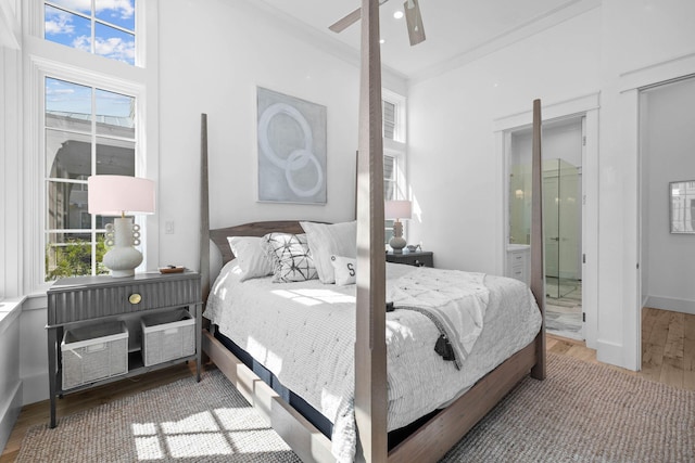 bedroom featuring ornamental molding, multiple windows, ceiling fan, and light wood-type flooring