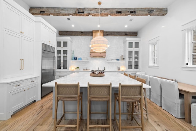 kitchen with a kitchen island, beam ceiling, a kitchen bar, and light wood-type flooring