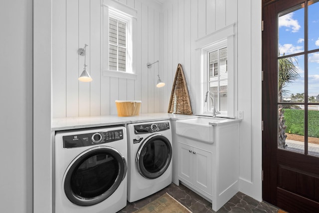 laundry room featuring cabinets, dark tile flooring, separate washer and dryer, and sink