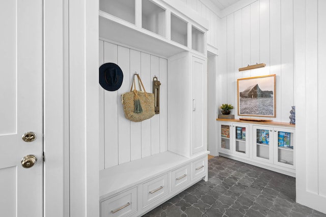 mudroom with ornamental molding and dark tile flooring