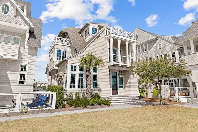 rear view of house with a yard and a balcony