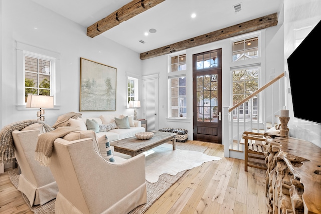 living room featuring plenty of natural light, light hardwood / wood-style flooring, and beamed ceiling