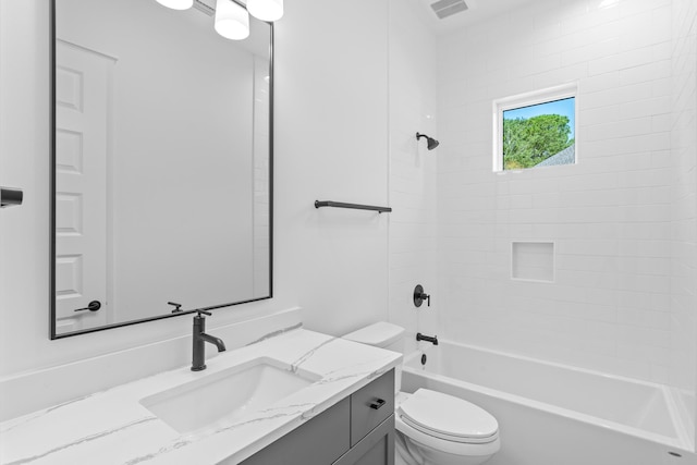 full bathroom featuring vanity, tiled shower / bath combo, and toilet