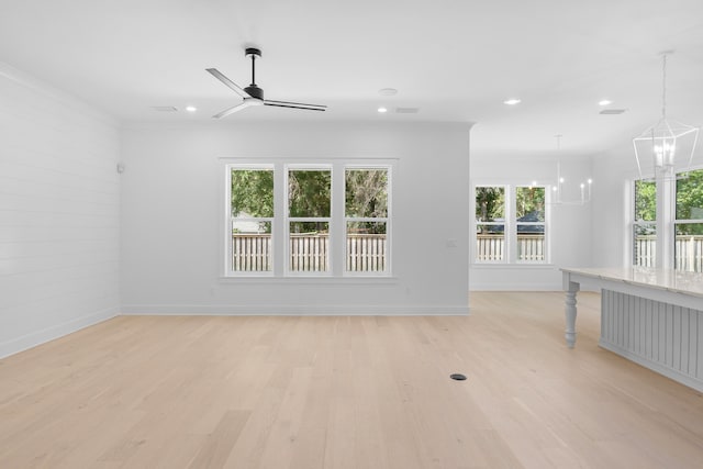 spare room featuring ceiling fan with notable chandelier, light hardwood / wood-style floors, a healthy amount of sunlight, and crown molding