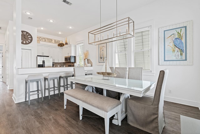 dining space with dark wood-type flooring and an inviting chandelier