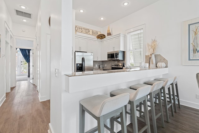 kitchen featuring plenty of natural light, white cabinetry, kitchen peninsula, and appliances with stainless steel finishes