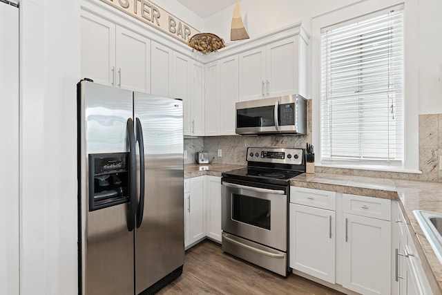 kitchen with white cabinets, stainless steel appliances, a wealth of natural light, and hardwood / wood-style flooring