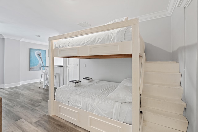 bedroom with hardwood / wood-style floors and ornamental molding