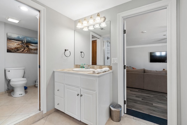 bathroom with tile patterned floors, vanity, toilet, and crown molding