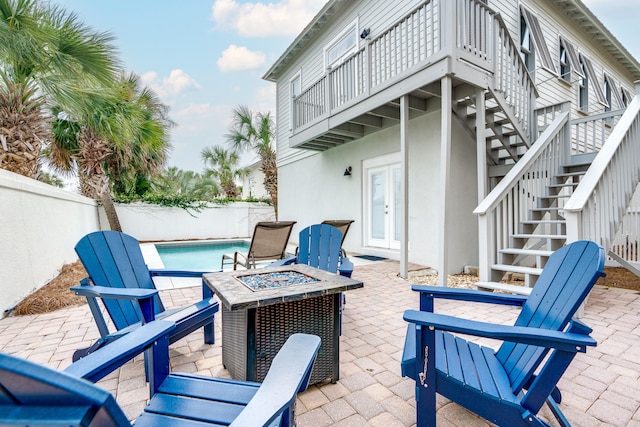 view of patio / terrace featuring a fenced in pool, french doors, a balcony, and a fire pit