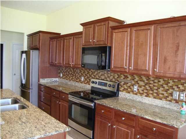 kitchen with appliances with stainless steel finishes, tasteful backsplash, and light stone counters