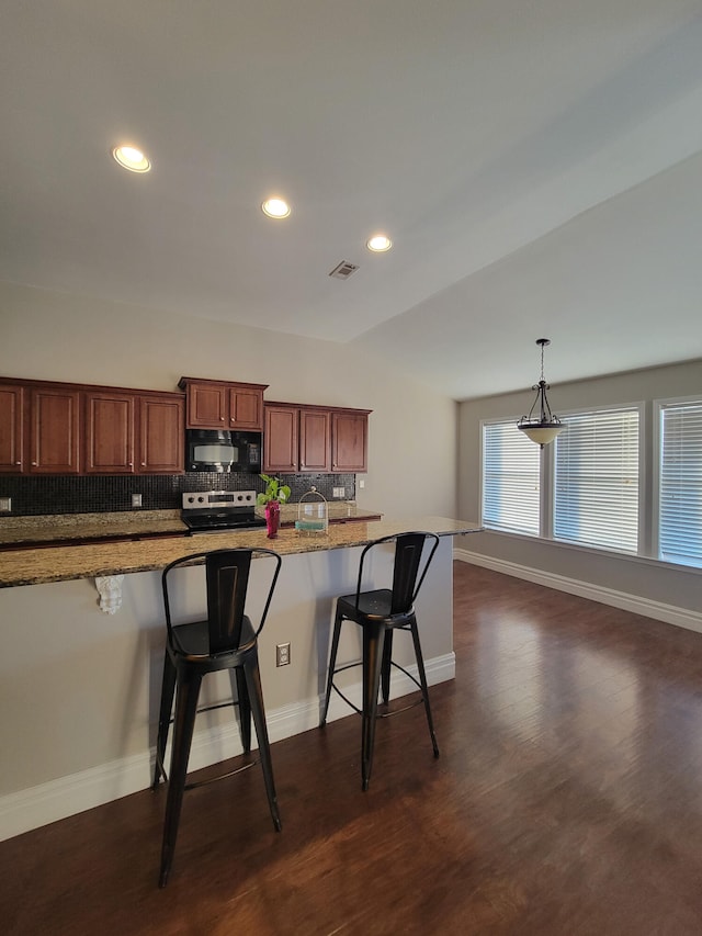 kitchen with a breakfast bar area, dark wood-type flooring, decorative backsplash, and light stone counters