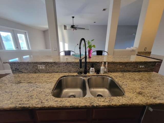 kitchen with sink, a kitchen island, light stone countertops, and ceiling fan