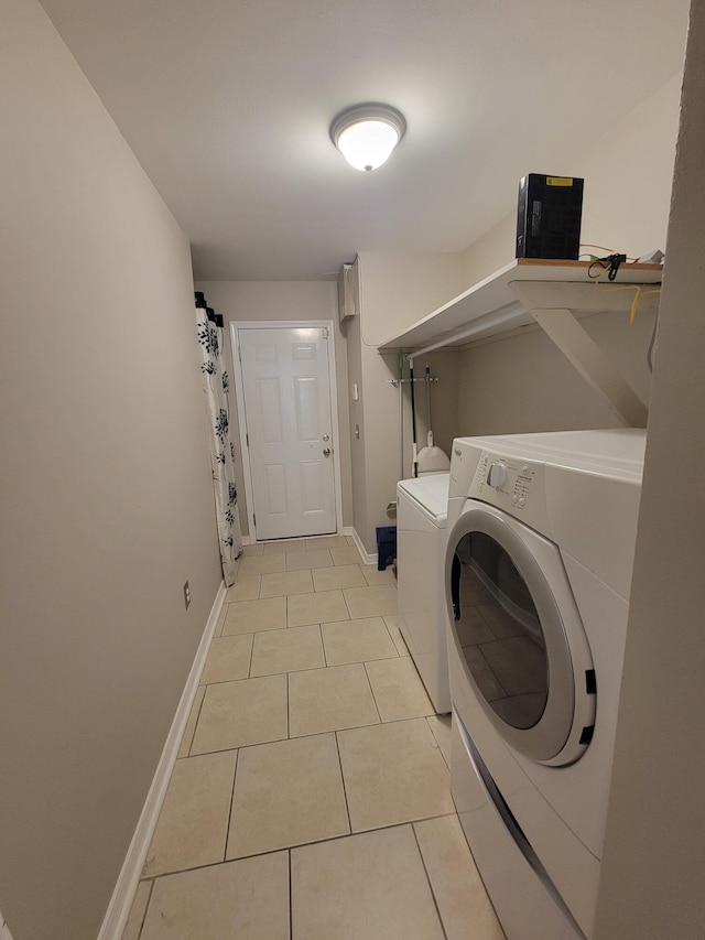 clothes washing area featuring washer and clothes dryer and light tile patterned floors