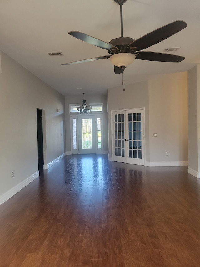 unfurnished living room featuring ceiling fan with notable chandelier, wood-type flooring, and french doors