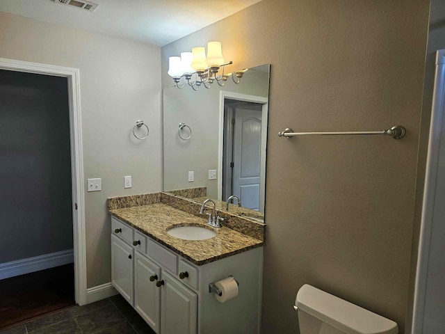 bathroom with tile patterned flooring, toilet, an inviting chandelier, and vanity