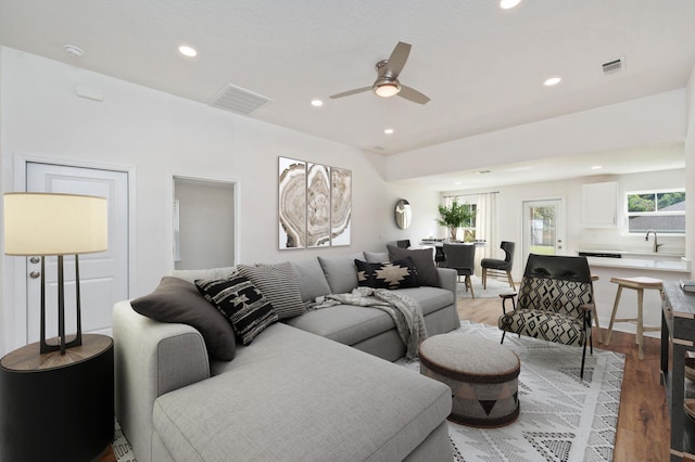 living room with wood-type flooring, ceiling fan, and sink