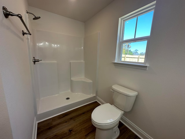 bathroom with hardwood / wood-style floors, toilet, and a shower