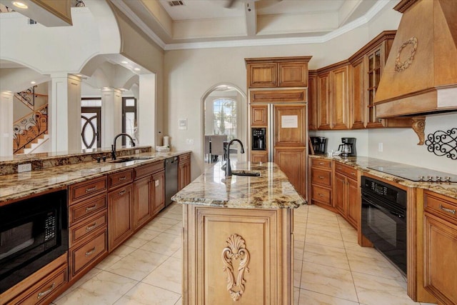 kitchen with premium range hood, sink, black appliances, and a kitchen island with sink