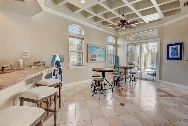 dining space featuring a high ceiling, light tile patterned floors, crown molding, and coffered ceiling