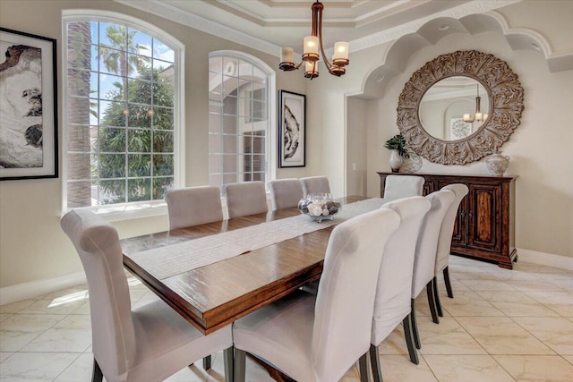 dining area featuring a raised ceiling, a chandelier, and ornamental molding