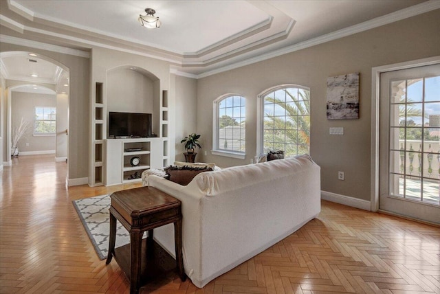 living room featuring light parquet floors, a raised ceiling, and ornamental molding