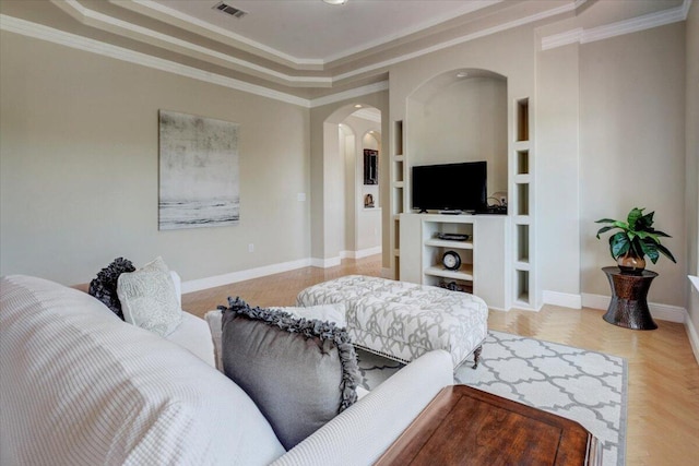 living room with built in shelves, crown molding, and light parquet floors