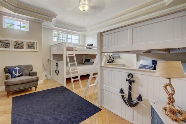 bedroom with ceiling fan, light parquet flooring, a tray ceiling, and crown molding