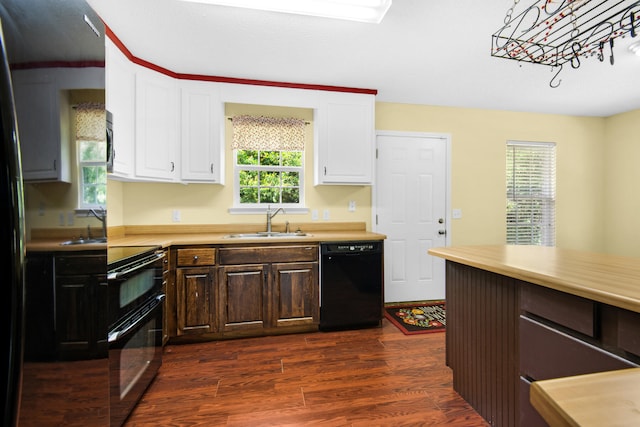 kitchen with dark wood-style flooring, light countertops, black appliances, white cabinetry, and a sink