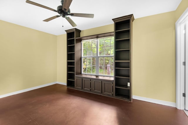 spare room with ceiling fan, finished concrete flooring, and baseboards