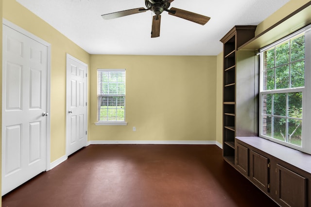 unfurnished bedroom with a ceiling fan, baseboards, and concrete flooring