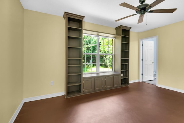 unfurnished room featuring finished concrete floors, a ceiling fan, and baseboards