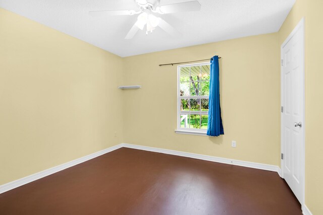 unfurnished room with dark wood-type flooring, a ceiling fan, and baseboards