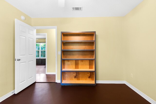 unfurnished room with dark wood-style flooring, visible vents, and baseboards