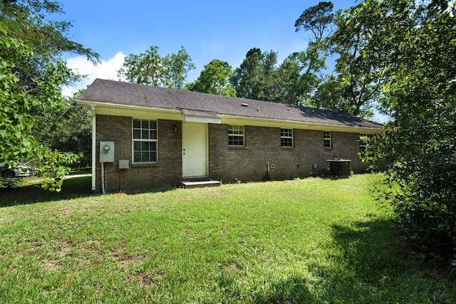 rear view of property with brick siding, a lawn, and central AC unit