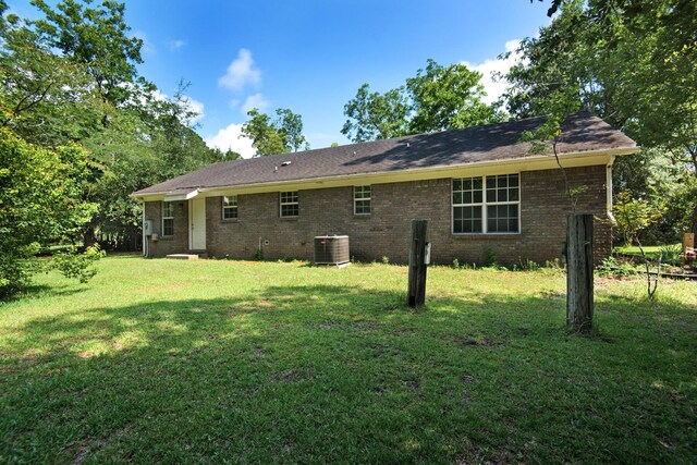 rear view of house featuring a yard, brick siding, and central AC unit